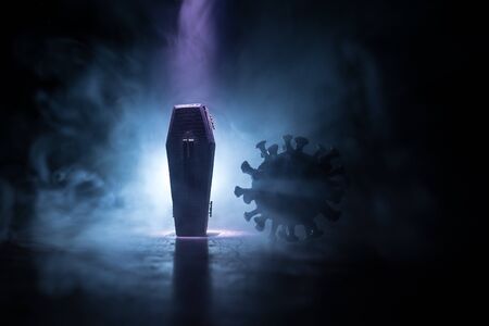 Creative artwork. Miniature wooden coffin on a table with dark background. Victims of coronavirus or...