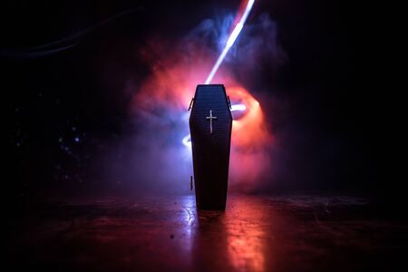 Creative artwork. Miniature wooden coffin on a table with dark background. Selective focus