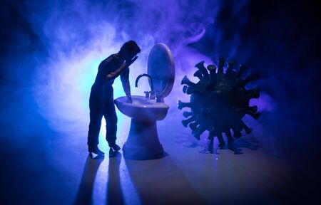 Miniature man washing hands at washstand on dark background. Hygiene concept. Wash hands protect yourself. Corona virus Prevention. Selective focusの写真素材