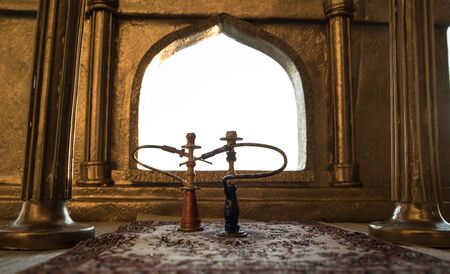Shisha concept. A realistic Arabian interior miniature with window and columns. Hookah hot coals on shisha bowl making clouds of steam. Stylish oriental shisha miniature. Selective focusの写真素材