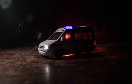 Corona virus concept with Ambulance car. Stay home for precautionary measures to prevent from corona virus. Ambulance car on dark misty background. Creative artwork decoration. Selective focusの写真素材