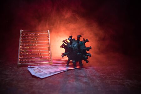 Corona virus global economy crisis concept. Corona virus miniature, money and abacus on wooden table with fog and backlight. Creative artwork decoration. Selective focus.の写真素材