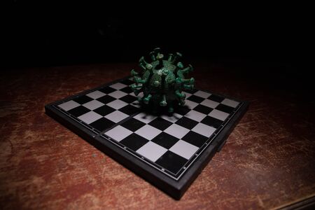 Chess board game concept strategy of business in Covid global pandemic. Big Corona virus miniature...