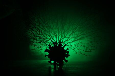 Coronavirus 2019-nCov novel coronavirus concept. Big Corona virus miniature model on wooden table with fog and backlight. Creative artwork decoration. Selective focus.の写真素材