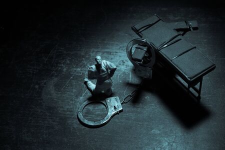 Lethal injection concept. Prisoner handcuffed to death by lethal injection. Creative artwork decoration with scale model on dark with lights.の写真素材