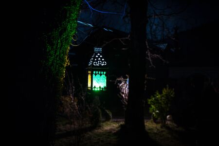 Beautiful colorful illuminated lamp in the garden in misty night. Retro style lantern at night...