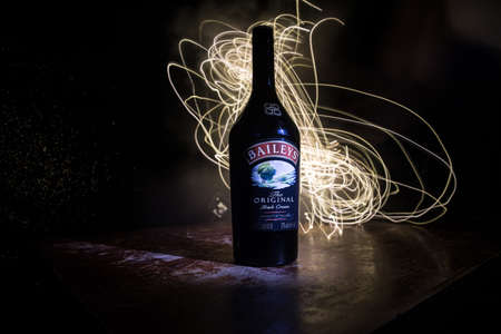 BAKU, AZERBAIJAN - FEB 09, 2020: Baileys Irish Cream is an Irish whiskey- and cream-based liqueur, made by Gilbeys of Ireland. A bottle of liqueur on wooden table with dark toned foggy background.のeditorial素材