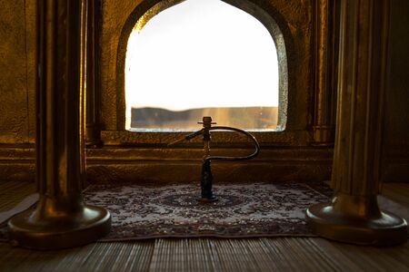 Shisha concept. A realistic Arabian interior miniature with window and columns. Hookah hot coals on shisha bowl making clouds of steam. Stylish oriental shisha miniature. Selective focusの写真素材