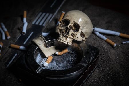 No smoking concept. Creative artwork table decoration with cigarettes. Cigarettes cause cancer and kill. still life skull and sigarette. Selective focusの写真素材