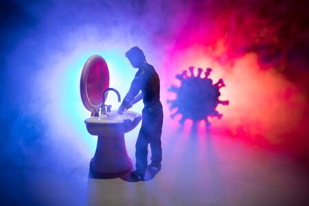 Miniature man washing hands at washstand on dark background. Hygiene concept. Wash hands protect yourself. Corona virus Prevention. Selective focusの写真素材
