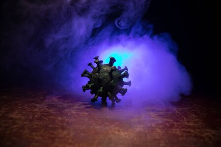 Coronavirus 2019-nCov novel coronavirus concept. Big Corona virus miniature model on wooden table with fog and backlight. Creative artwork decoration. Selective focus.の写真素材