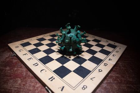 Chess board game concept strategy of business in Covid global pandemic. Big Corona virus miniature model on chessboard with fog and backlight. Creative artwork decoration. Selective focusの写真素材