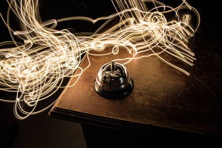 Calling service bell on wooden table with toned lights on dark background. Hotel reception bell, service bell on the table, selective focusの写真素材