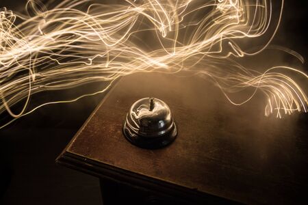 Calling service bell on wooden table with toned lights on dark background. Hotel reception bell, service bell on the table, selective focusの写真素材