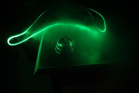 Calling service bell on wooden table with toned lights on dark background. Hotel reception bell, service bell on the table, selective focusの写真素材