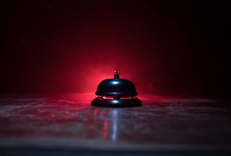 Calling service bell on wooden table with toned lights on dark background. Hotel reception bell, service bell on the table, selective focusの写真素材