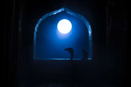 A realistic Arabian interior miniature with window and columns. Silhouette of muslim praying on carpet near window. Festive greeting card, invitation for Muslim holy month Ramadan Kareem. Selective focusの写真素材