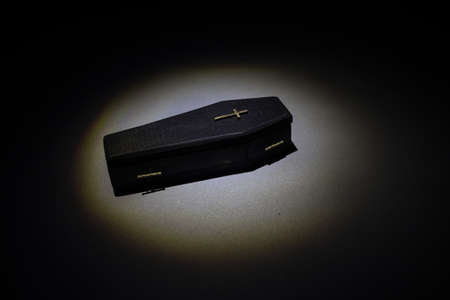 Creative artwork. Miniature wooden coffin on a table with dark background. Selective focusの写真素材