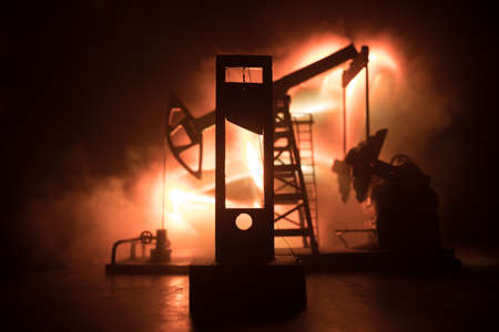 Oil industry crisis concept. Oil stock crisis because Covid global pandemic. Oil pump and oil refining factory at night with fog and backlight. Creative artwork decoration. Selective focus.の写真素材