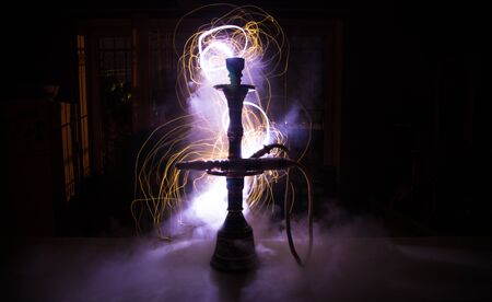 Hookah hot coals on shisha bowl making clouds of steam at dark room. Stylish oriental shisha in dark...