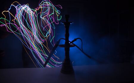 Hookah hot coals on shisha bowl making clouds of steam at dark room. Stylish oriental shisha in dark with backlight. Selective focusの写真素材