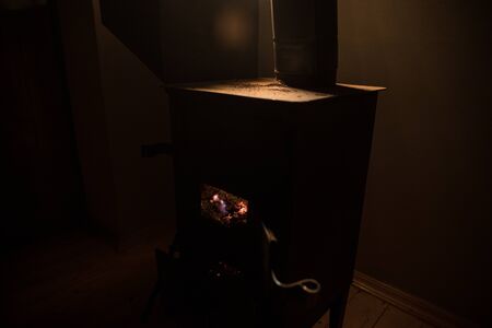 Fire burning in small black iron stove. Traditional Azerbaijani nut stove. Closeup photo with...