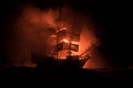 Black silhouette of the pirate ship in night. night scene of ghost pirate ship in the sea with mysterious light. Selective focusの写真素材