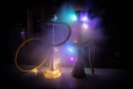 Hookah hot coals on shisha bowl making clouds of steam at dark room. Stylish oriental shisha in dark with backlight. Selective focusの写真素材