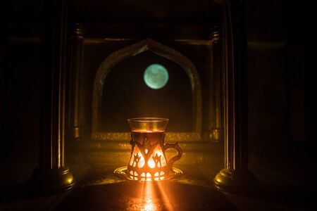 Arabian tea concept. A realistic Arabian interior miniature with window and columns. Arabian tea in glass inside room. Low light lounge interior with carpet. Selective focusの写真素材