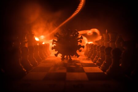 Chess board game concept strategy of business in Covid global pandemic. Big Corona virus miniature model on chessboard with fog and backlight. Creative artwork decoration. Selective focusの写真素材