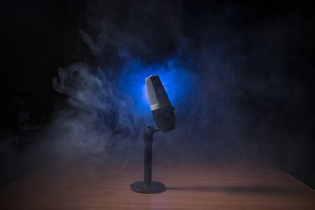 Microphone for sound, music, karaoke in audio studio or stage. Mic technology. Speech broadcast equipment. Microphone in dark room on table with backlight. Selective focusの写真素材