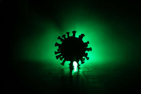 Coronavirus 2019-nCov novel coronavirus concept. Big Corona virus miniature model on wooden table with fog and backlight. Creative artwork decoration. Selective focus.の写真素材