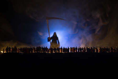 Coronavirus 2019-nCov novel coronavirus concept. Crowd looking on a grim reaper at night with fog and backlight. Creative artwork decoration. Selective focus.の写真素材