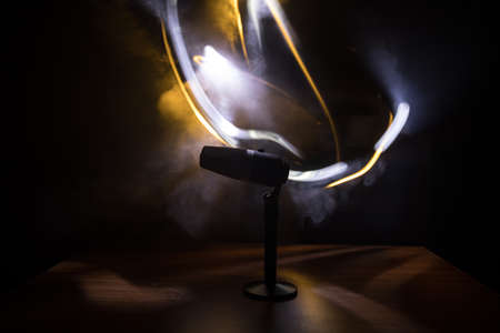 Microphone for sound, music, karaoke in audio studio or stage. Mic technology. Speech broadcast equipment. Microphone in dark room on table with backlight. Selective focusの写真素材