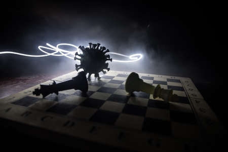 Chess board game concept strategy of business in Covid global pandemic. Big Corona virus miniature model on chessboard with fog and backlight. Creative artwork decoration. Selective focusの写真素材