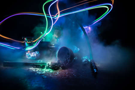 Shisha concept. Preparing shisha on table. Used shisha bowl on wooden table. Dark atmosphere with...