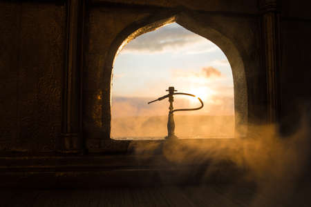 Shisha concept. A realistic Arabian interior miniature with window and columns. Hookah hot coals on shisha bowl making clouds of steam. Stylish oriental shisha miniature. Selective focusの写真素材