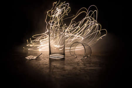 Drink, broken glass concept. Broken glasses on wooden table at dark toned background with fog....