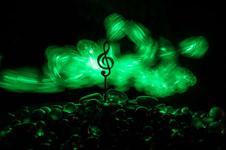 Music concept. Musical symbol treble clef stainless steel miniature with colorful toned light on...