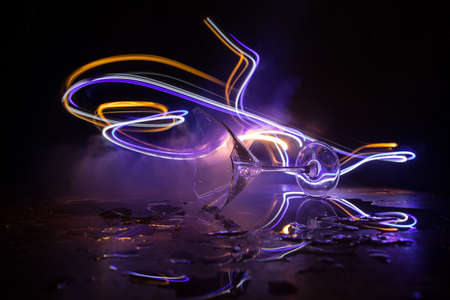 Drink, broken glass concept. Broken glasses on wooden table at dark toned background with fog....
