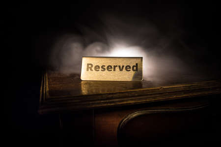 Reserved sign on the table. A tag of reservation placed on the wood table. Metal tag with...