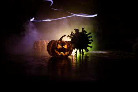 Halloween during Corona virus global pandemic concept. Glowing pumpkins and Covid novel on dark with...