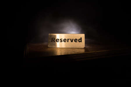 Reserved sign on the table. A tag of reservation placed on the wood table. Metal tag with...