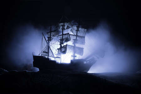 Black silhouette of the pirate ship in night. night scene of ghost pirate ship in the sea with mysterious light. Selective focusの写真素材