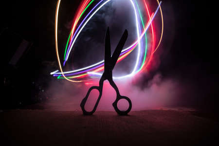 Silhouette of tailor`s scissors on wooden table in low light. Artwork decoration with toned foggy...