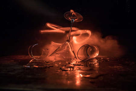 Drink, broken glass concept. Broken glasses on wooden table at dark toned background with fog. Selective focusの写真素材