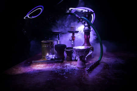 Shisha concept. Preparing shisha on table. Used shisha bowl on wooden table. Dark atmosphere with light. Selective focus.の写真素材