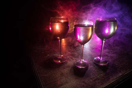 Goblet of wine on wooden table with beautiful toned lights on background. Glasses of wine on dark...