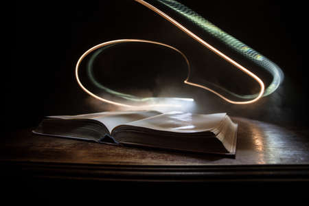 A stack of old books. Vintage book on wooden table. Magic lightning around a glowing book in the...