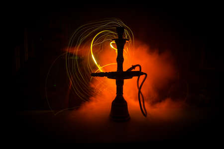 Hookah hot coals on shisha bowl making clouds of steam at dark room. Stylish oriental shisha in dark...